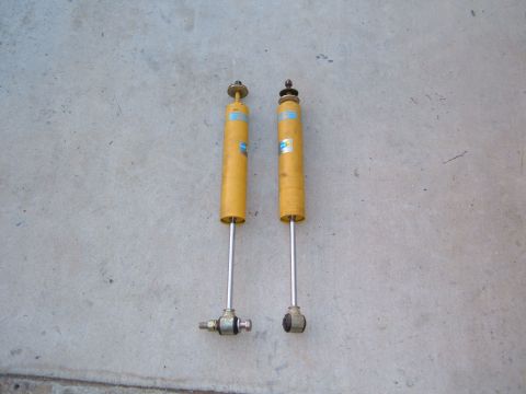 1985 Ford Bronco II - Two yellow Bilstein shock absorbers are displayed against a concrete surface. The registry claims they are from a 1985 Ford Bronco II, but…