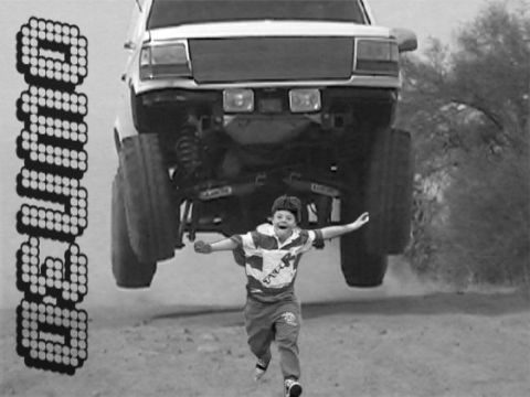 1968 Ford Mustang - A child runs as a lifted truck soars overhead, with pixelated text on the left side of the frame.