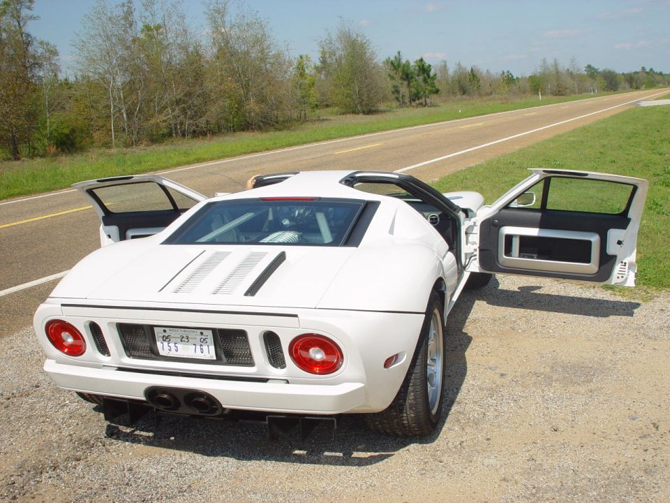 White Ford GT on a rural roadside with both doors open, rear three-quarter view