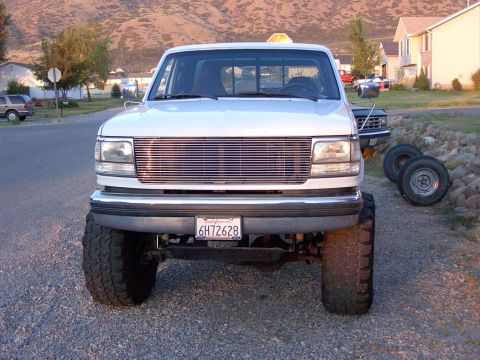 1992 Ford F-150 - This lifted 1992 Ford F-150 has a prominent chrome grille and is parked on a gravel surface.