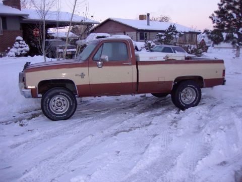 1992 Ford F-150 - A two-tone pickup truck sits in a snowy driveway, with a car parked behind it under a carport.