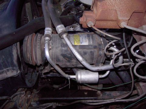 1992 Ford F-150 - Vehicle AC compressor with hoses and filter drier visible in engine bay.