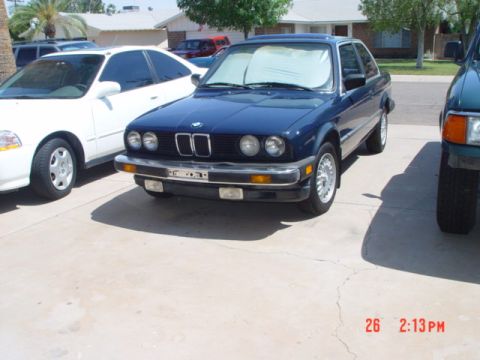 1992 Ford F-150 - A blue BMW coupe is parked in a driveway next to a white sedan and a green SUV. The front grille and headlights are visible.