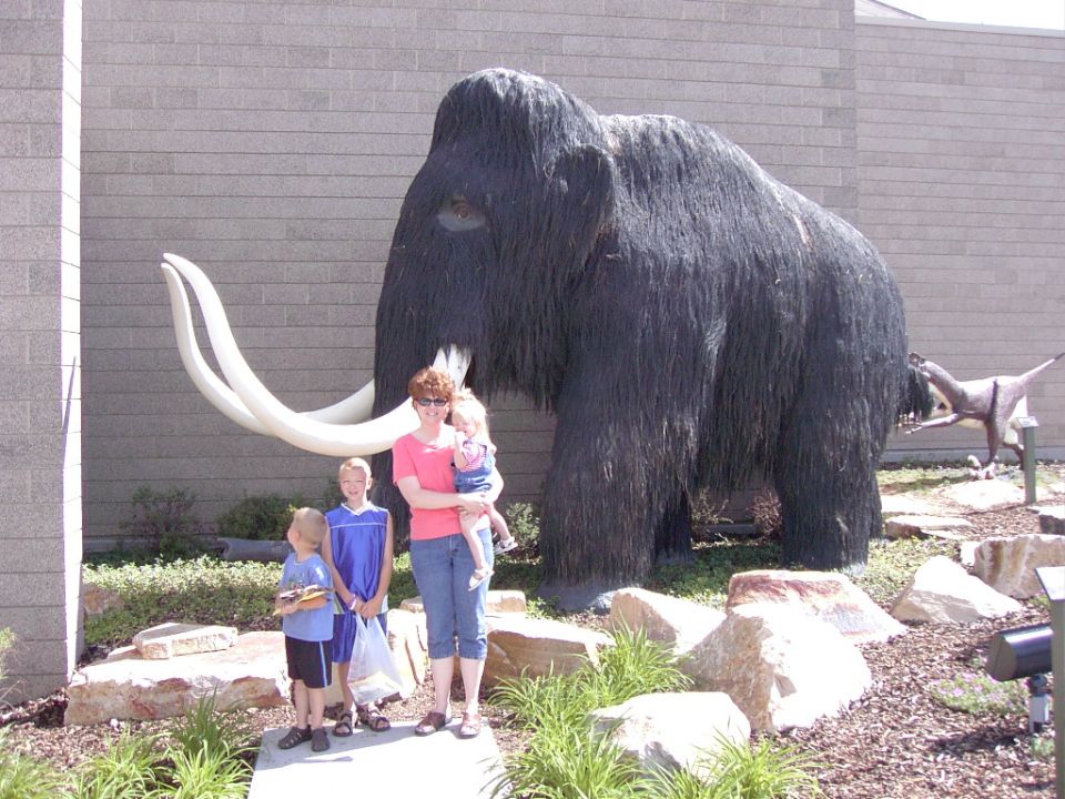 Mammoth statue with a family posing in front of a brick building