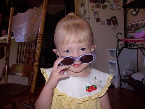 1992 Ford F-150 - A young child with blonde hair and bangs plays dress-up with oversized sunglasses.