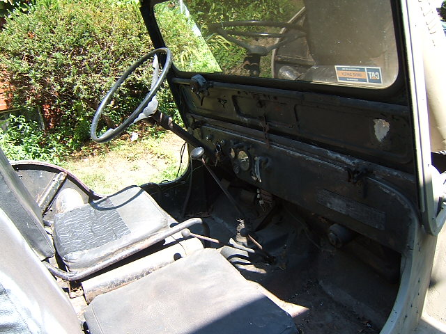 Jeep interior with black seats, steering wheel, and dashboard. A sticker is visible on the windshield