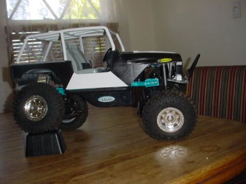 1988 Ford Bronco - RC crawler model vehicle with a white roll cage and black body is displayed on a table.