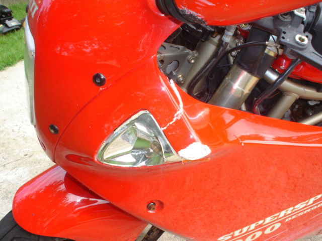Front-left red fairing of a Ducati Supersport 900 with headlight and cracked bodywork