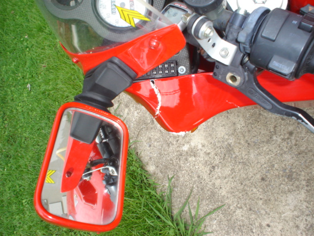 Red motorcycle left fairing with crack, mirror, and handlebar controls