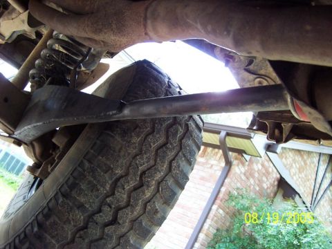 1987 Ford Bronco - A close-up view of a vehicle's undercarriage, revealing suspension parts and a tire.