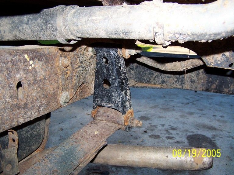 Close-up of rusty vehicle frame with suspension parts and a black bracket. Date stamp reads 08/19/2005