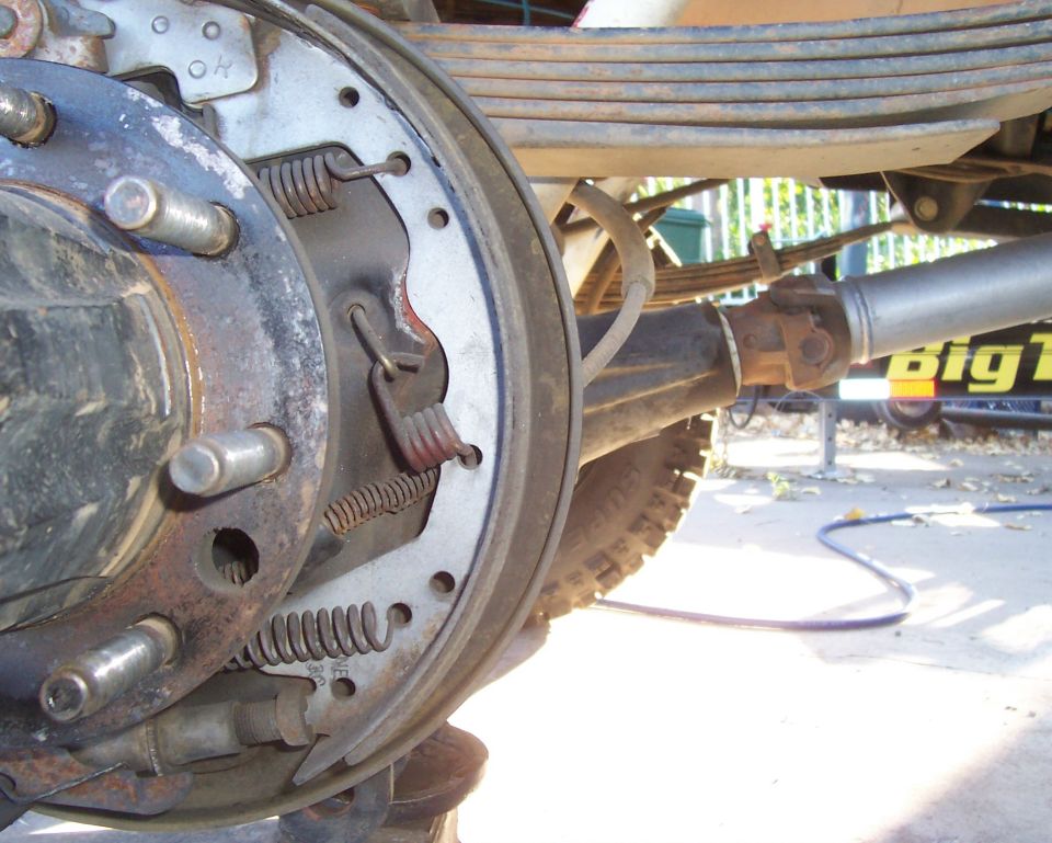 Close-up of a rear drum brake assembly with leaf springs and driveshaft visible
