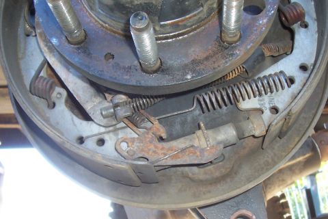 1994 Ford F-150 - Close-up of a disassembled rear drum brake showing the shoes, return springs, adjuster and backing plate, with surface rust.