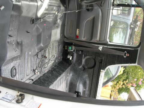 1994 Ford Bronco - The interior of a vehicle shows a black spray-on bedliner applied to the floor and lower walls, with exposed wiring.