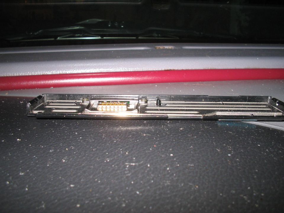 Close-up of a black plastic car interior part with a multi-pin connector