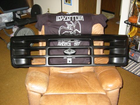 1996 Ford Bronco - A freshly painted flat-black Ford truck/Bronco front grille shell removed from the vehicle and propped on a tan leather recliner indoors. T…