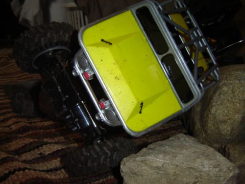 1992 Ford Bronco - A yellow toy RC car is shown on its side amidst rocks and carpet, revealing its interior details.