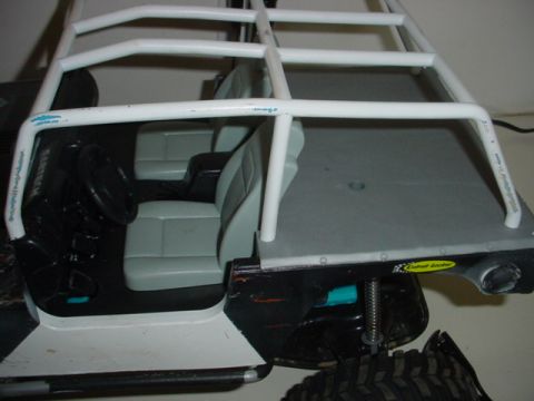 1988 Ford Bronco - The interior of a remote control crawler vehicle is shown, a roll cage and grey seats.