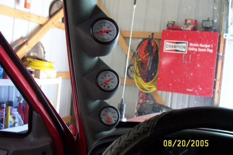1995 Ford F-350 - A vehicle's interior features a gauge pod with three meters, a steering wheel, and a Champion spark plug toolbox.