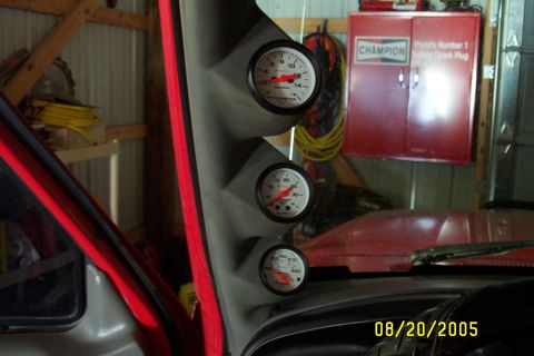 1995 Ford F-350 - Three gauges are mounted on a pillar inside a red vehicle, with a red cabinet in the background.