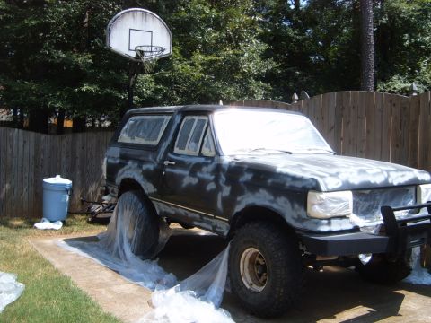 1988 Ford Bronco - A black Ford Bronco is prepped for painting, covered in primer and plastic sheeting.