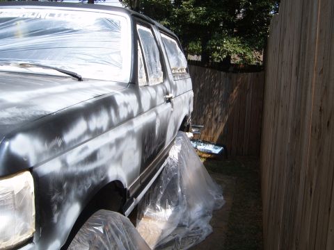 1988 Ford Bronco - This SUV is covered in plastic sheeting and primer, indicating it is undergoing preparation for a new paint job.