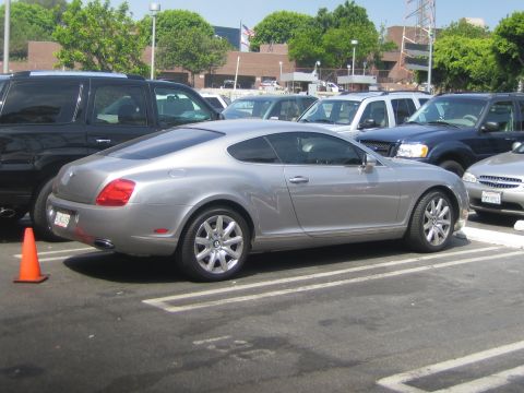 1968 Ford Mustang - Silver Bentley Continental GT coupe parked in a lot with other vehicles.