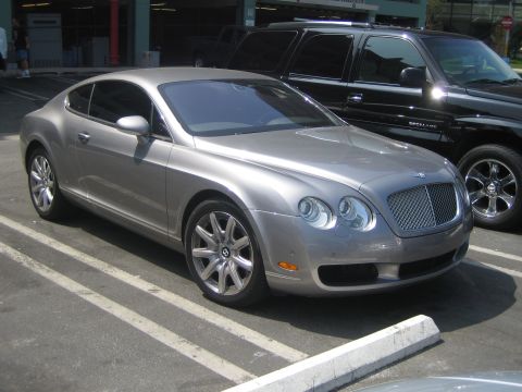 1968 Ford Mustang - A silver Bentley Continental GT is parked next to a black SUV.