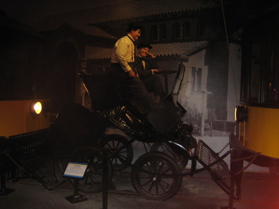 Mannequins dressed in old-fashioned clothes sit in a black horse-drawn carriage