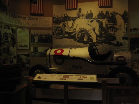 1968 Ford Mustang - A Stutz race car, identified by the number 8 and the Stutz badging, is displayed indoors with historical racing imagery on the wall.