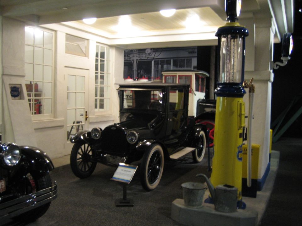 Black vintage car with white-wall tires parked next to a yellow gas pump