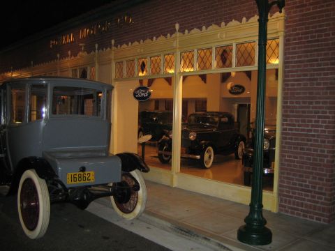 1968 Ford Mustang - Exterior view of a vintage Ford dealership at night, showing cars displayed in the showroom.
