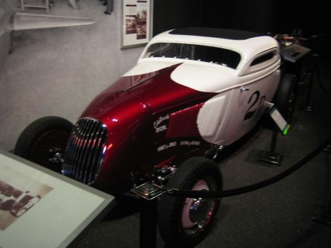1968 Ford Mustang - A custom hot rod with a two-tone paint scheme and racing numbers is displayed indoors.