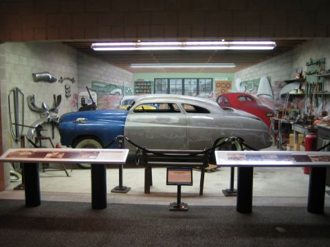 1968 Ford Mustang - A workshop scene displays a car undergoing customization, with another vehicle visible behind it.