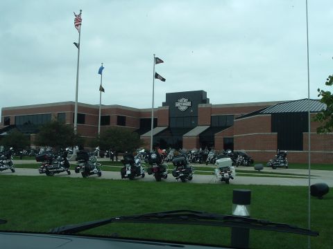 1995 Mercury Grand Marquis - A large collection of motorcycles are parked outside a building with American flags flying.