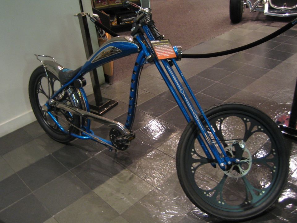 Blue custom chopper motorcycle with ornate front wheel and teardrop gas tank