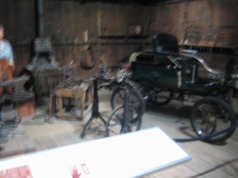 1968 Ford Mustang - An early automobile with spoked wheels is displayed in a workshop environment, surrounded by tools and equipment.