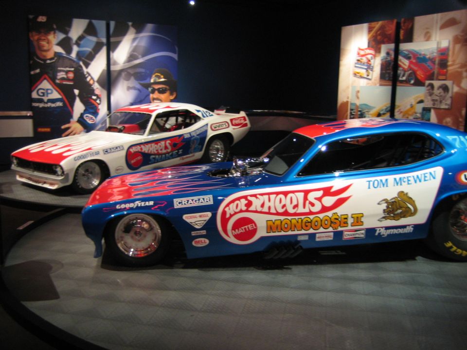 Blue and white dragster with "Hot Wheels Mongoose II" and "Tom McEwen" text, next to a white and red dragster with "Hot Wheels Snake II" text
