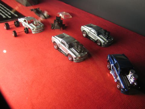 1968 Ford Mustang - A collection of model cars, some with custom engine modifications, are displayed on a red cloth surface.