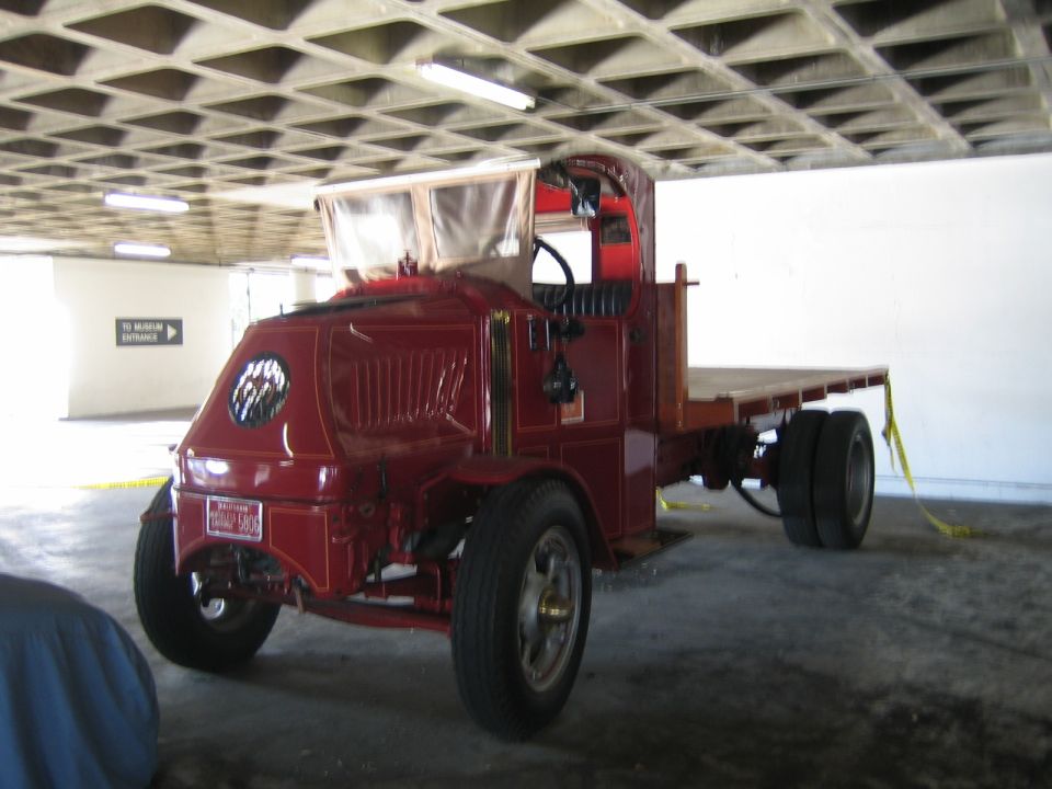 Red flatbed truck with a vintage design, a prominent grille and a flat cargo bed