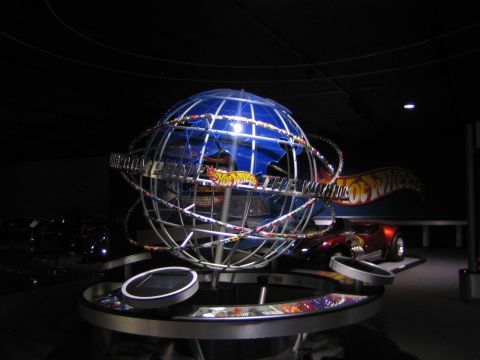 1968 Ford Mustang - A Hot Wheels display features a globe and a red sports car in a dimly lit exhibition space.