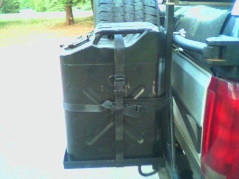 1993 Ford Bronco - Close-up of a black military-style jerry can strapped into a shop-built steel carrier bolted to the rear corner of a truck, with a mounted…