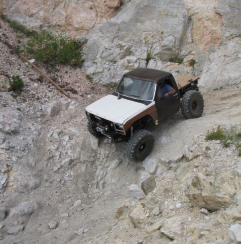 1981 Ford Bronco - A modified pickup truck navigates a steep, rocky off-road trail.