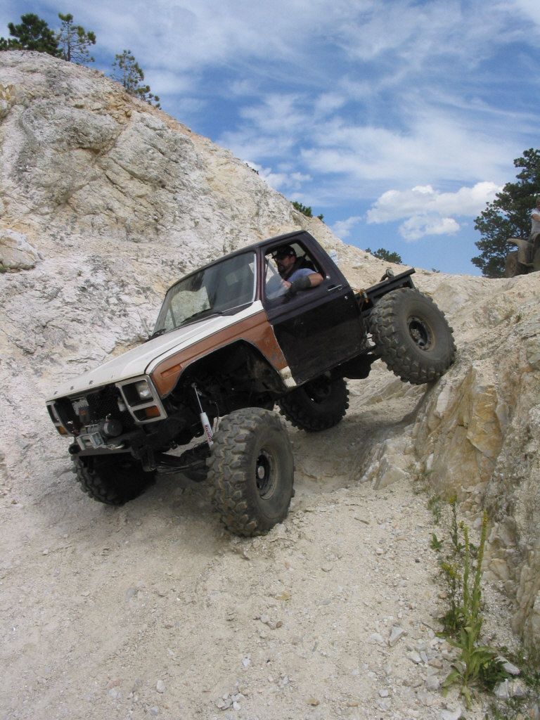 Topless brown and white Ford 4x4 with winch dropping off a white rock ledge