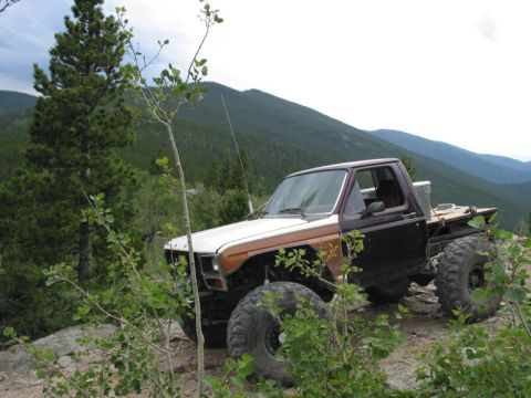 1981 Ford Bronco - This modified pickup truck, likely from the early 1980s, navigates a steep, rocky mountain path.