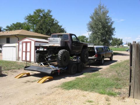 1981 Ford Bronco - A modified off-road truck is loaded onto a trailer behind another pickup truck.