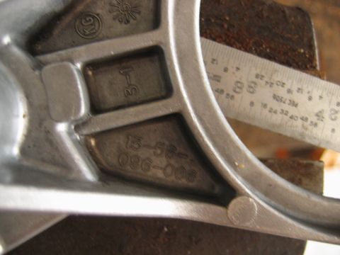1992 Ford Bronco - Close-up of a cast aluminum vehicle part showing embossed markings including a 'KG' logo, a sunburst symbol, '3T', and casting numbers '13-…
