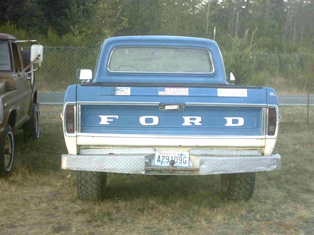 Rear of a blue and white Ford pickup with FORD tailgate lettering in a field