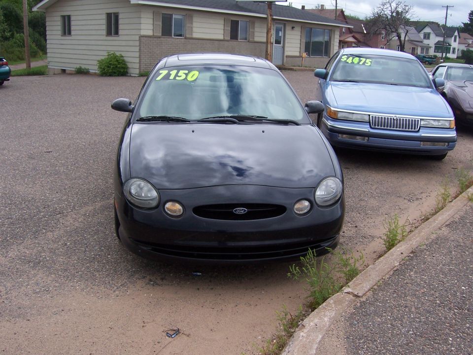 Black 1996 Ford Taurus front view, with a yellow '7150' sticker on the windshield