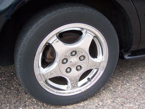 1996 Mercury Sable - Close-up of a chrome five-spoke wheel and black tire on a dark-colored vehicle.